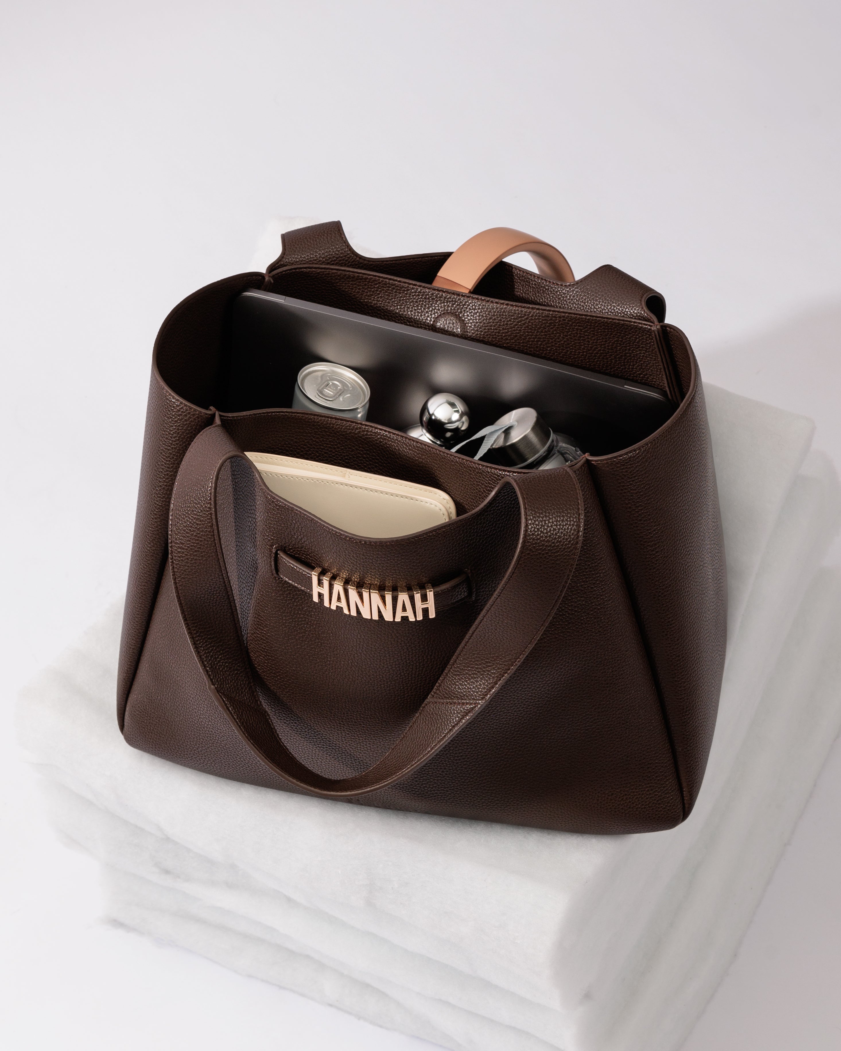 Brown handbag with 'HANNAH' personalisation on a white surface