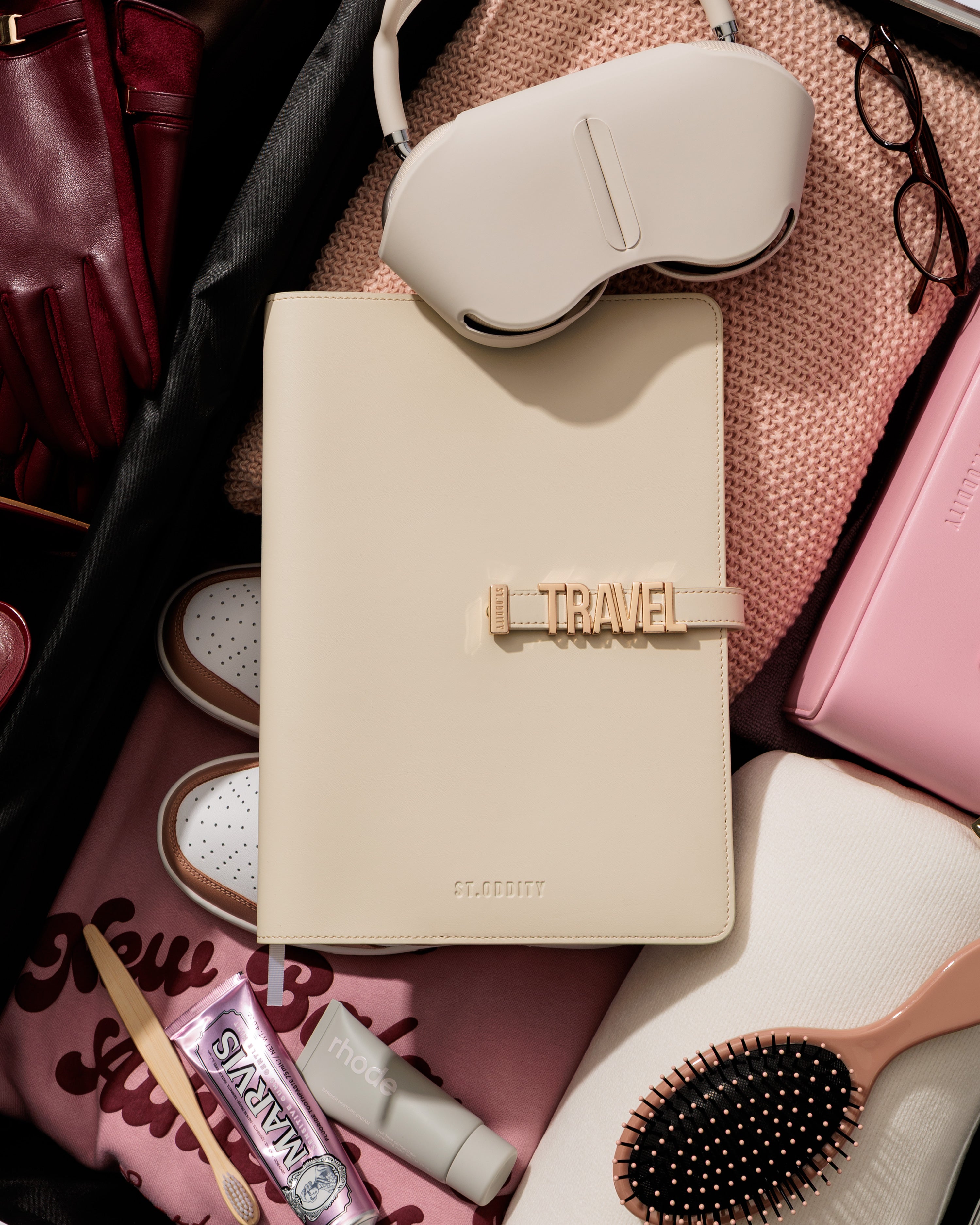 Off white A4 Notebook personalised with 'TRAVEL' in gold hardware, sitting in a suitcase, surrounded by travel essentials.