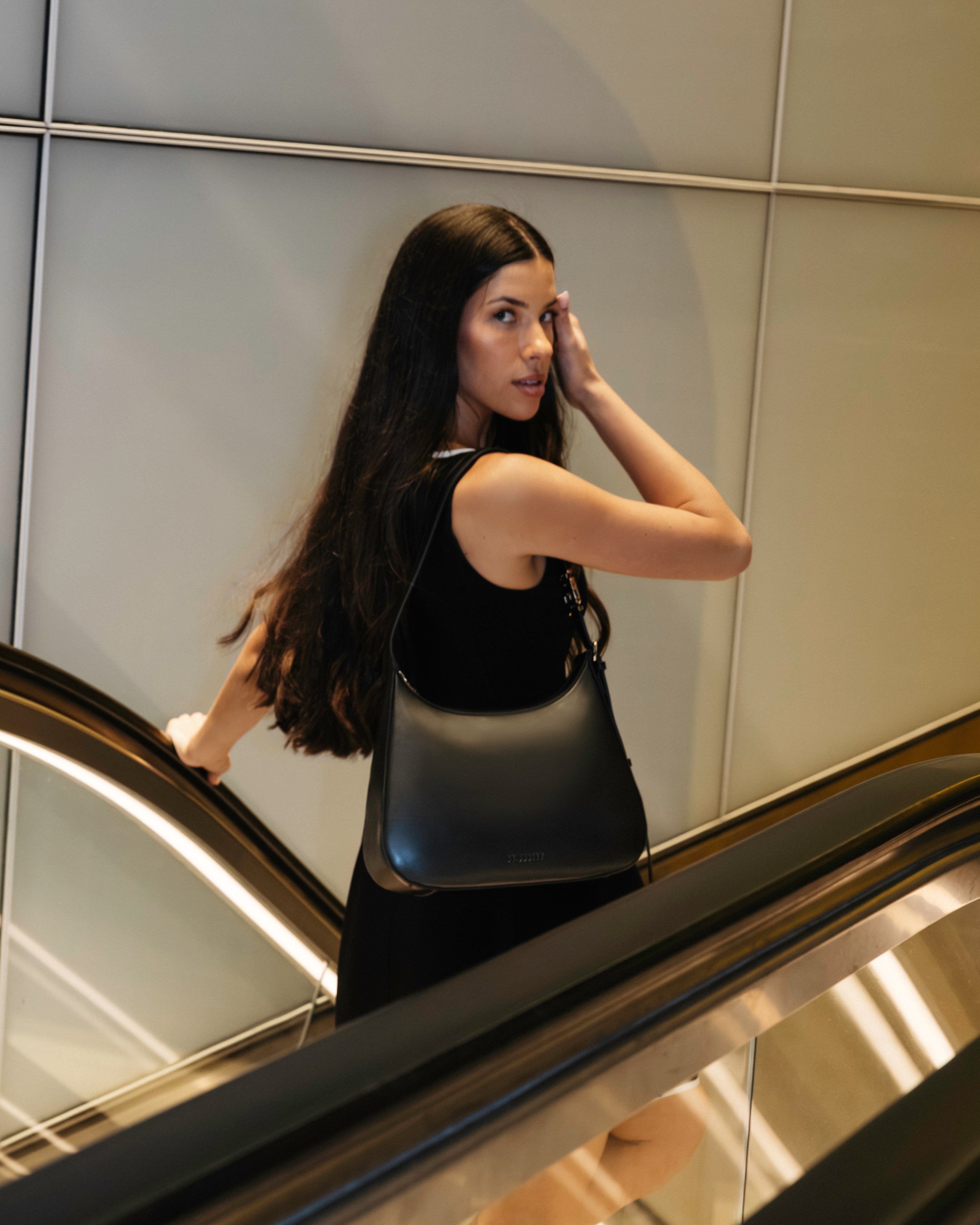 Model wearing black handbag on escalator