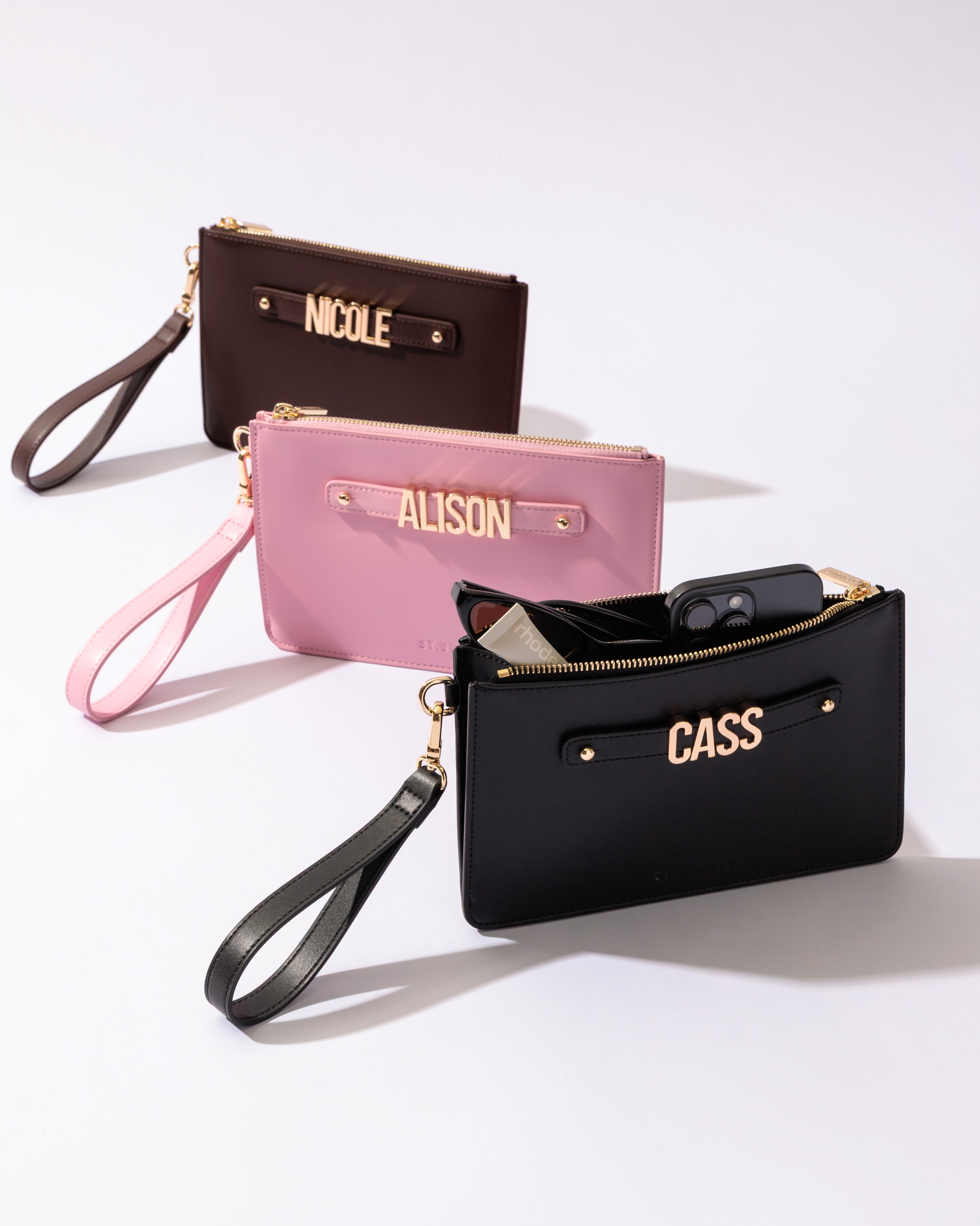 Three pouches in brown, pink and black with gold personalisation on a white background