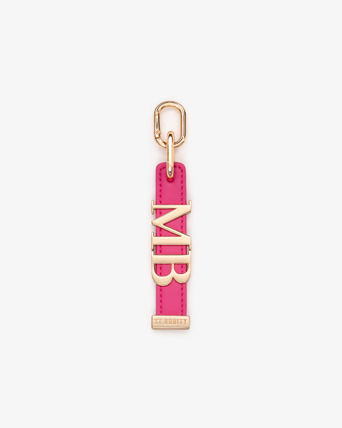 A pink charm featuring gold-tone metal hardware, including a top loop, a vertical strap, and serif initials.