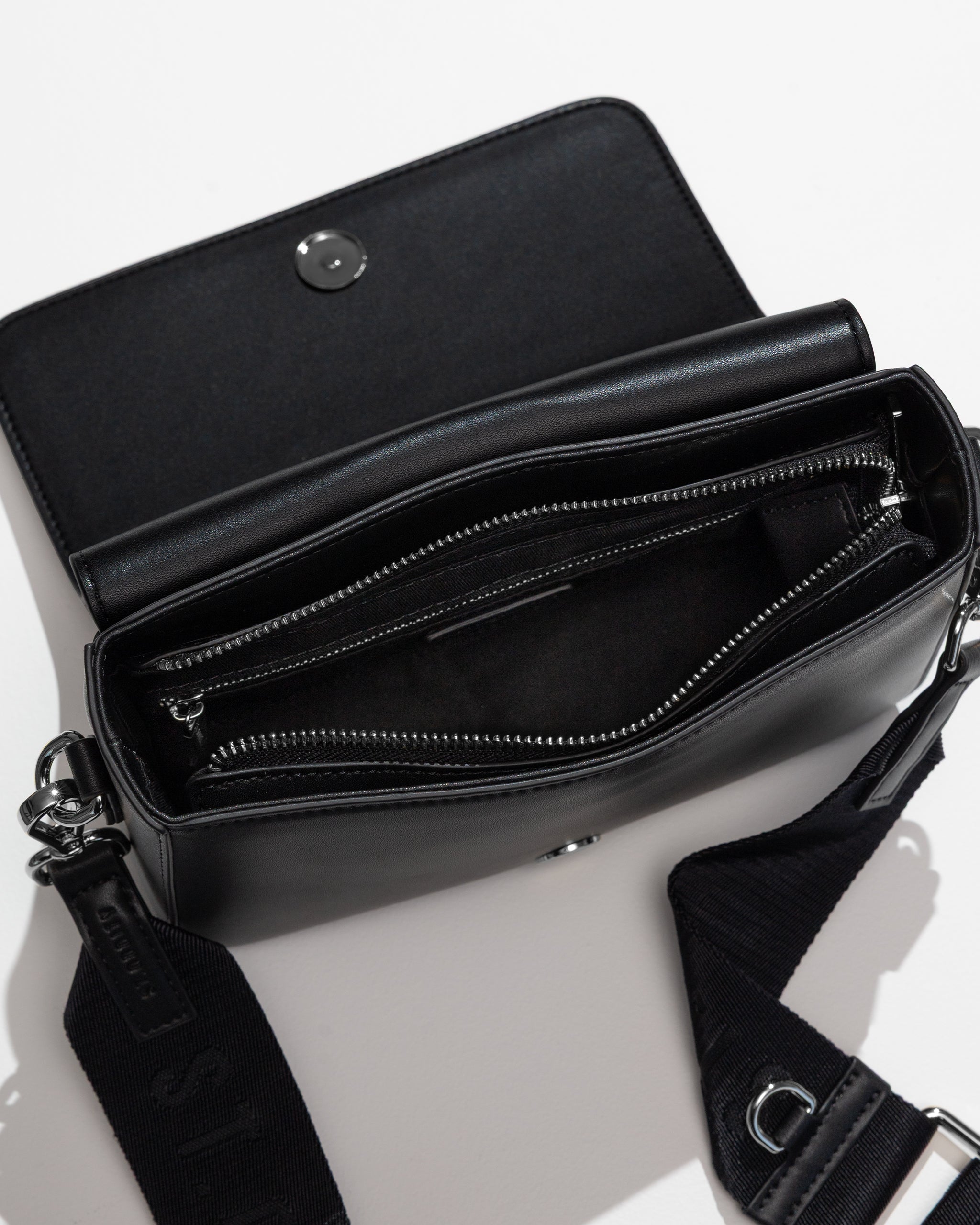 Open black crossbody bag with zip and internal pockets on a white background