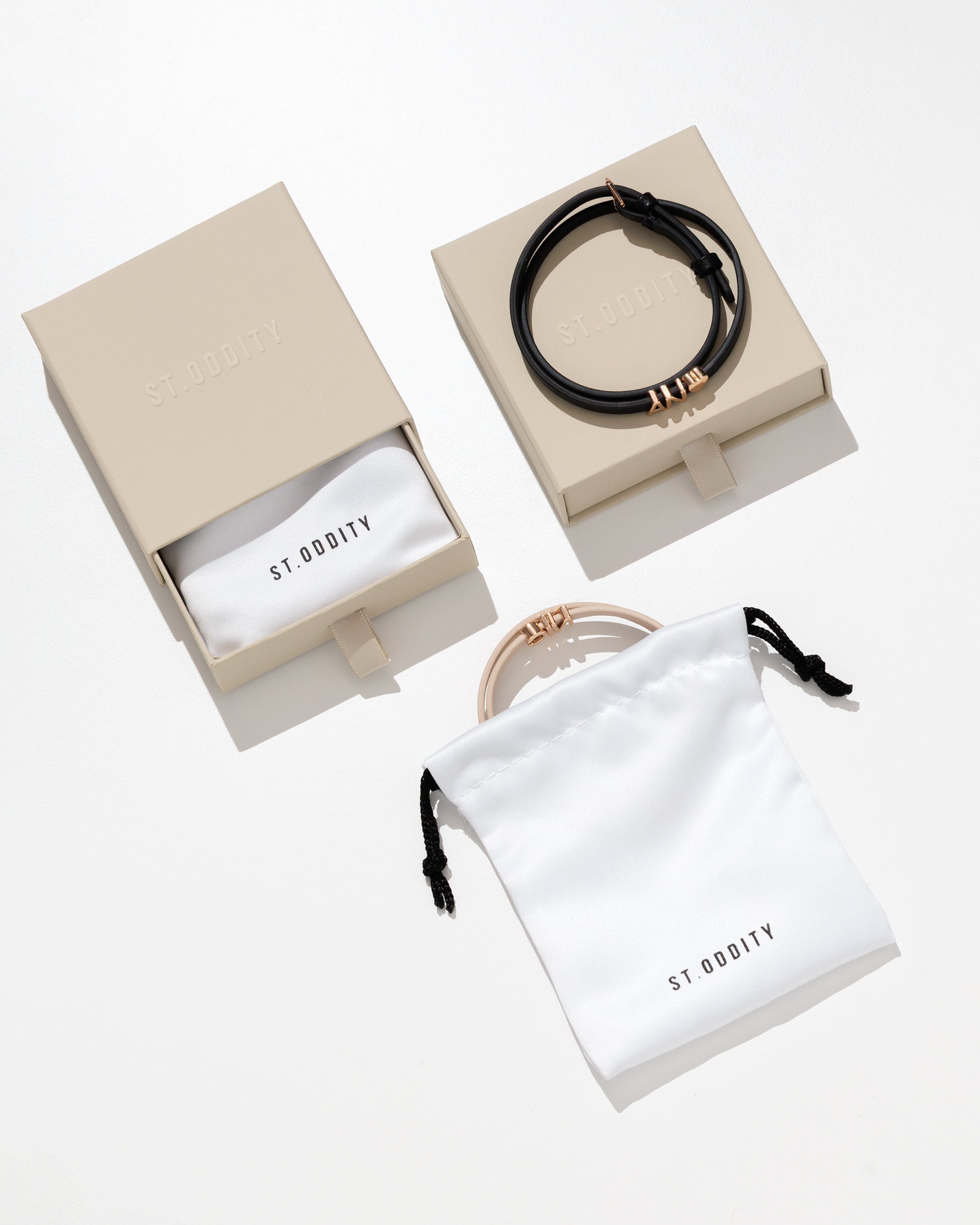 Jewelry set with personalised bracelets in branded boxes and a pouch on a white background.