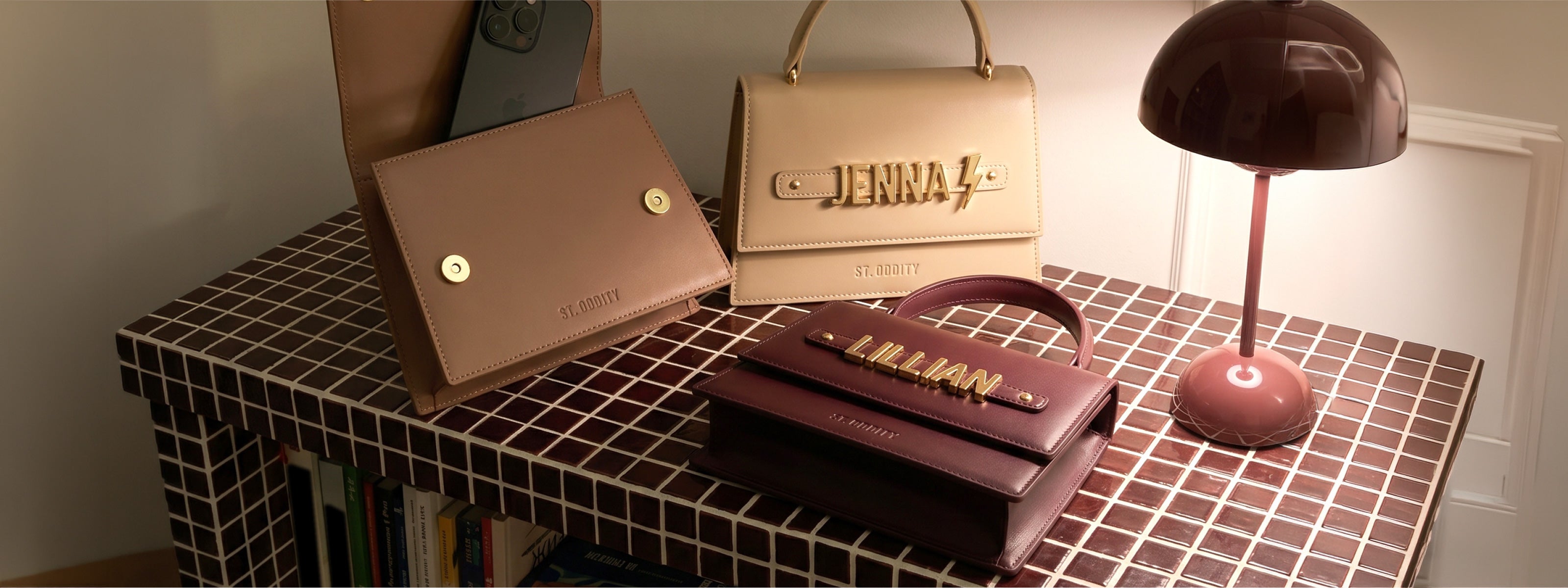Three hand bags with a top handle and personalisation a checkered surface with a lamp.