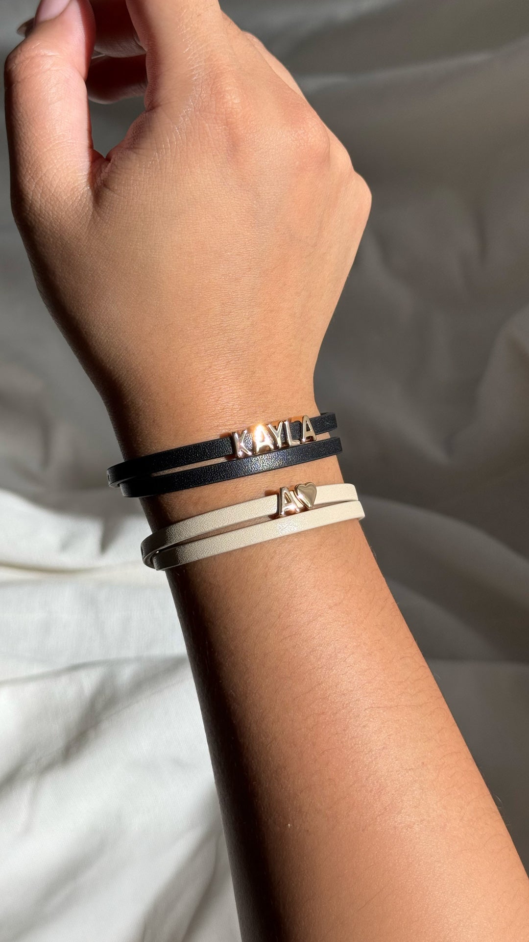 Hand wearing multiple bracelets on a neutral background