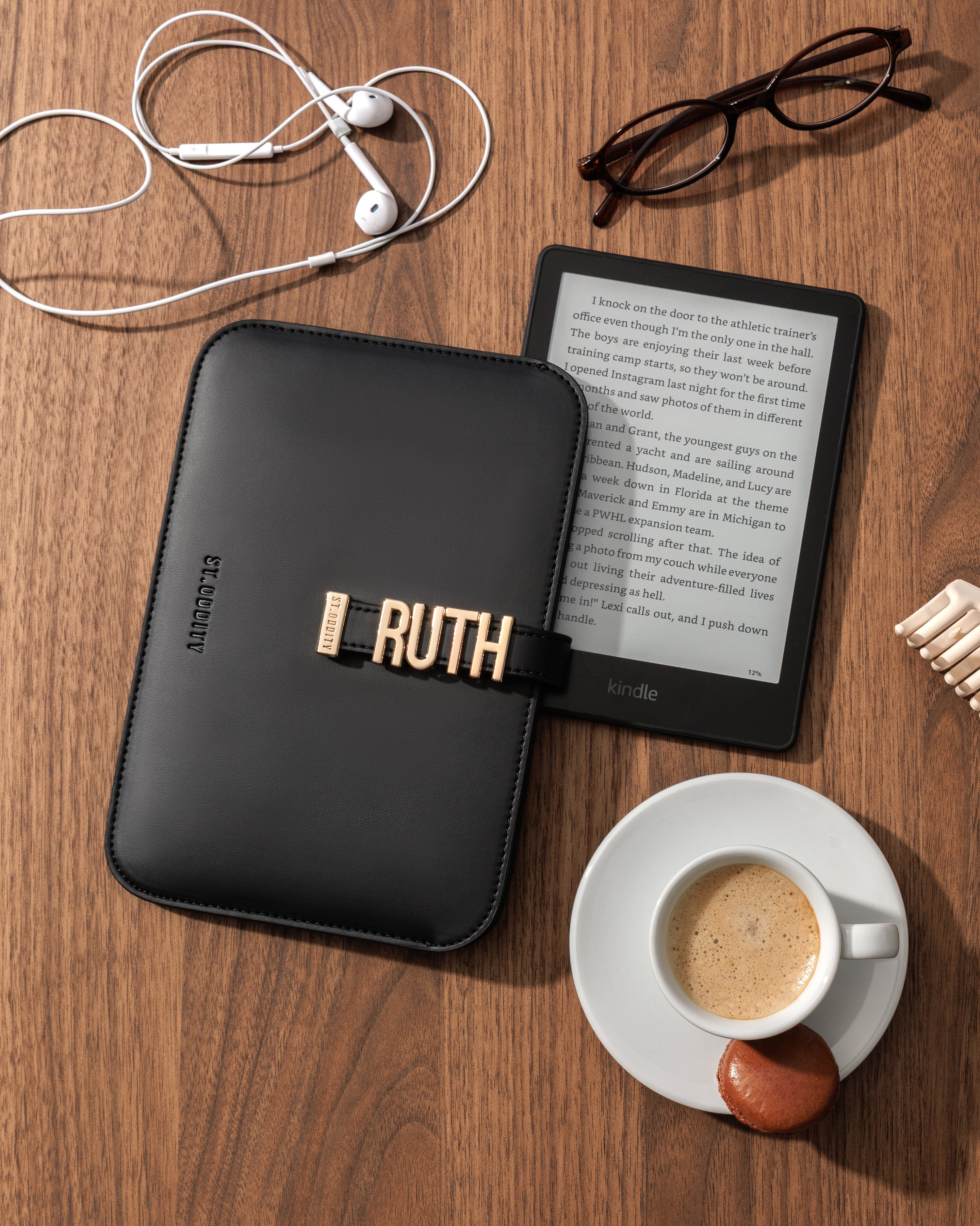 Black kindle sleeve with essentials on a wooden table