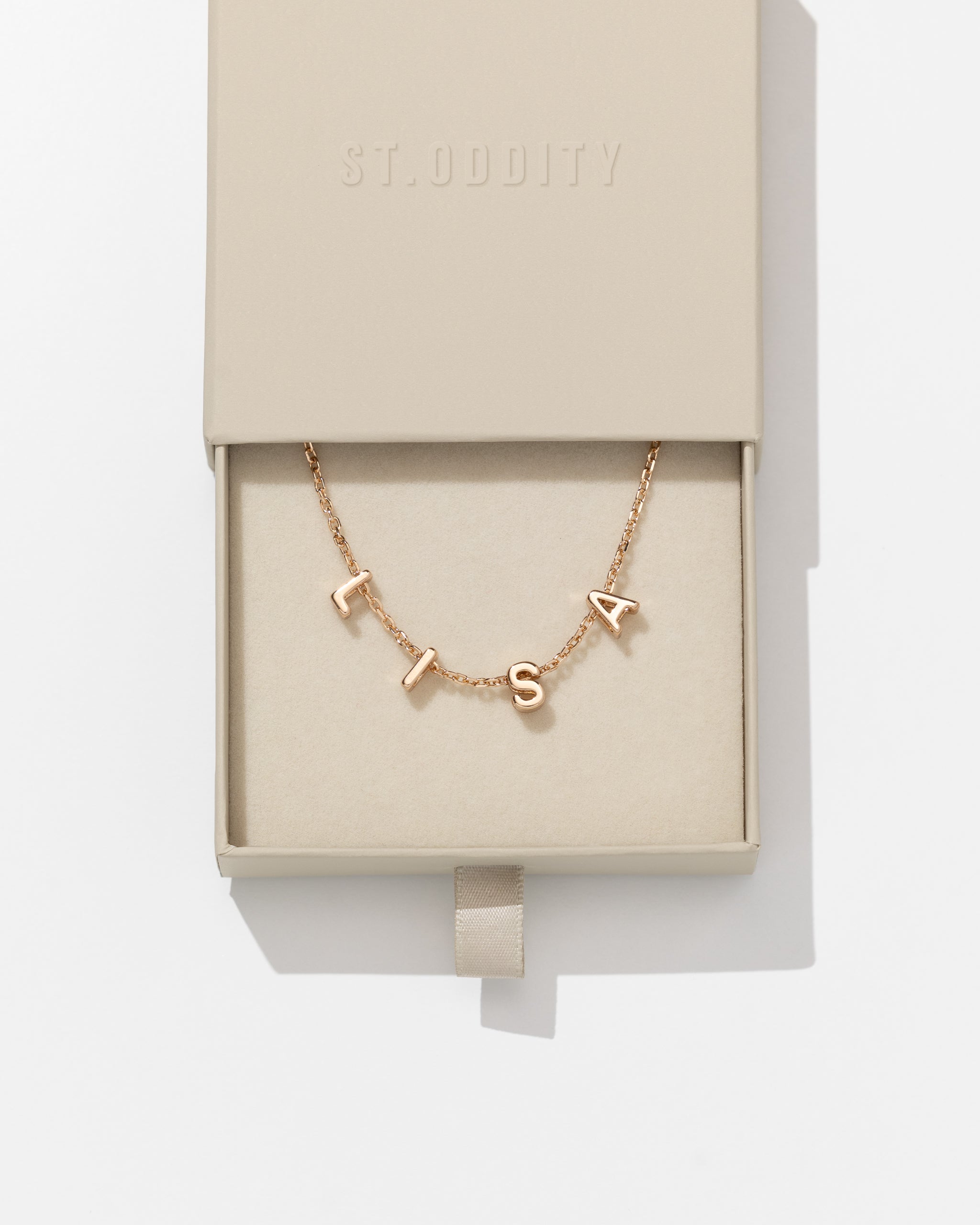 Gold fine chain necklace with 'BEC' personalised on it in beige box