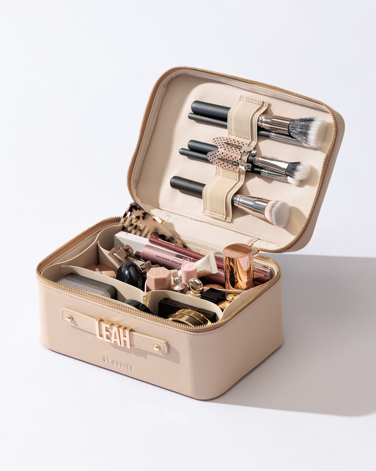 Vanity Case in Light Sand with Light Beige lining filled with brushes and cosmetics.