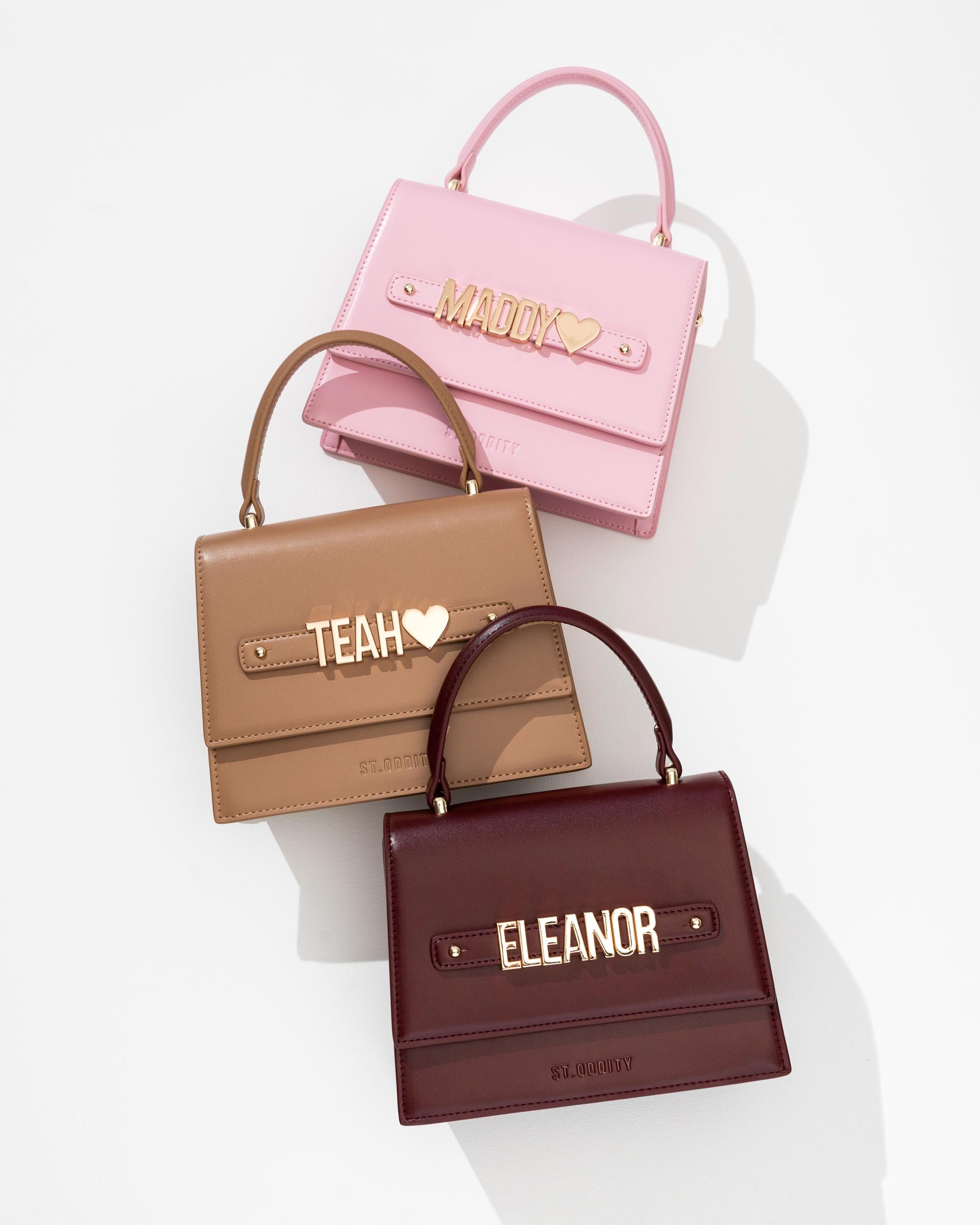Three handbags in pink, mocha, and oxblood with personalised names on a white background