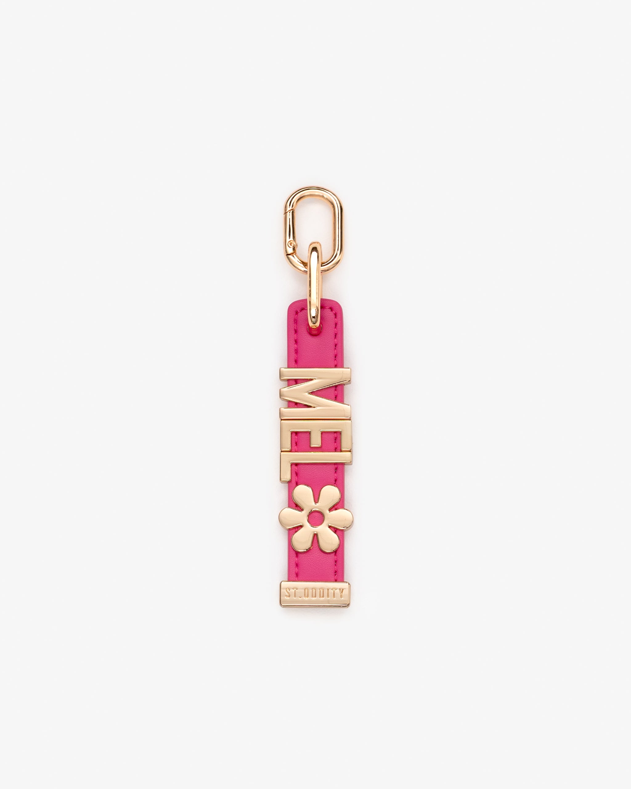 A pink charm featuring gold-tone metal hardware, including a top loop, a vertical strap, and standard initials.