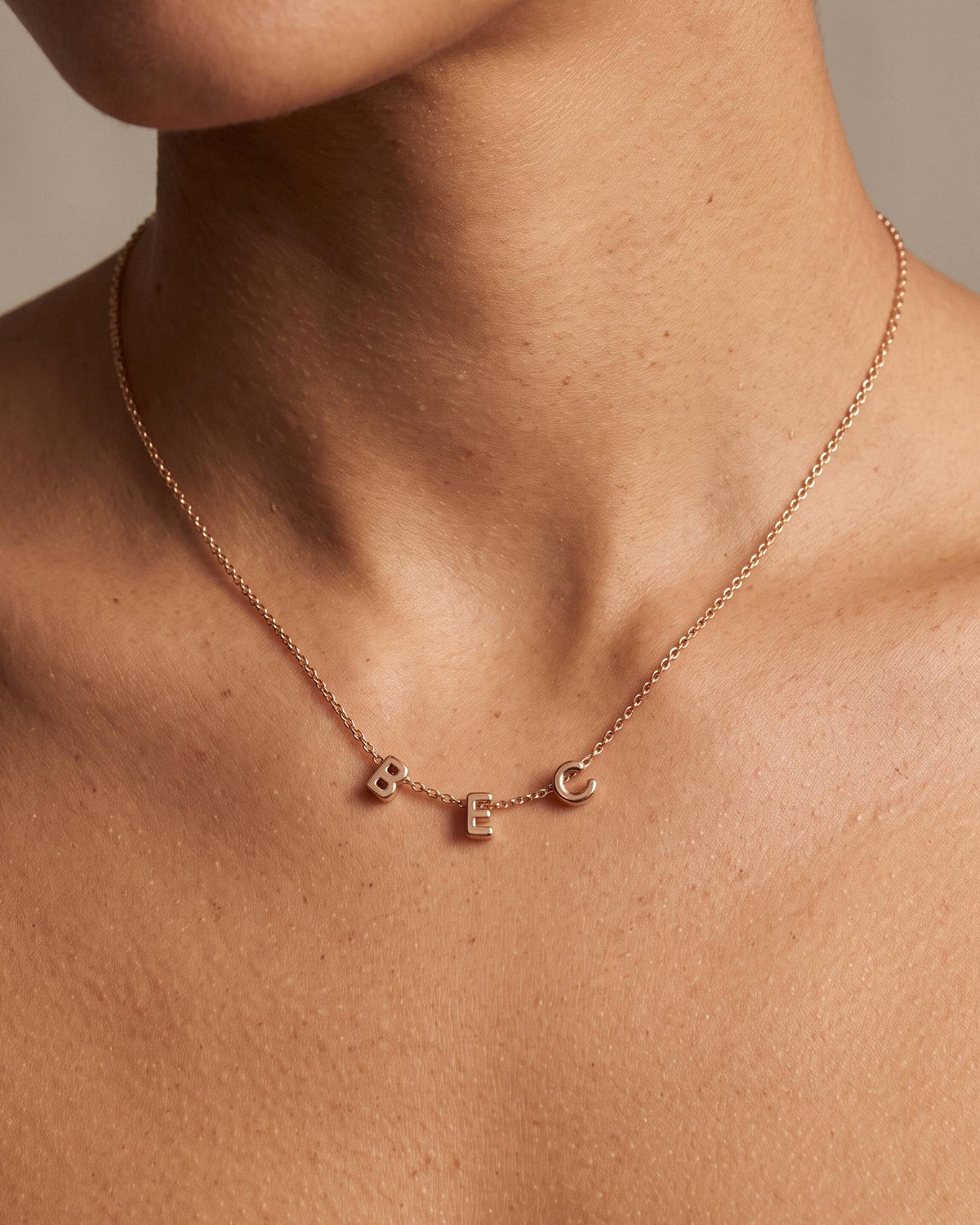 Letter Necklace in Gold personalised with 'BEC' worn on a female model.