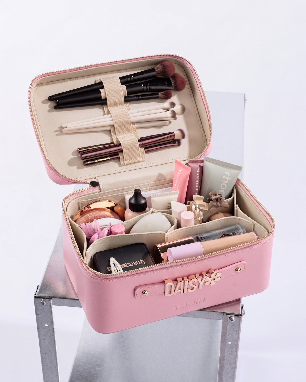 Pink makeup case with various cosmetic items on a white background