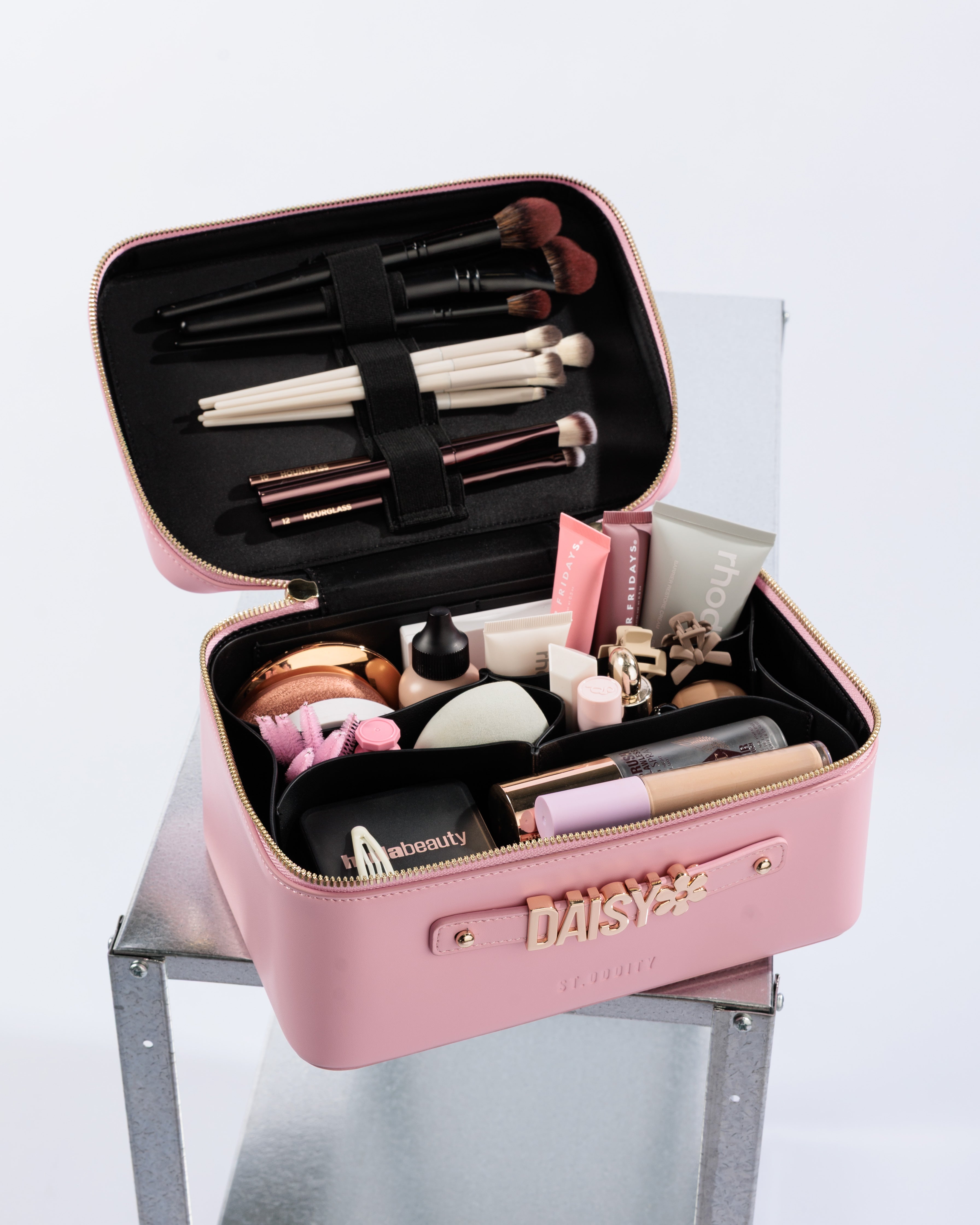 Pink makeup case with various cosmetic items on a white background